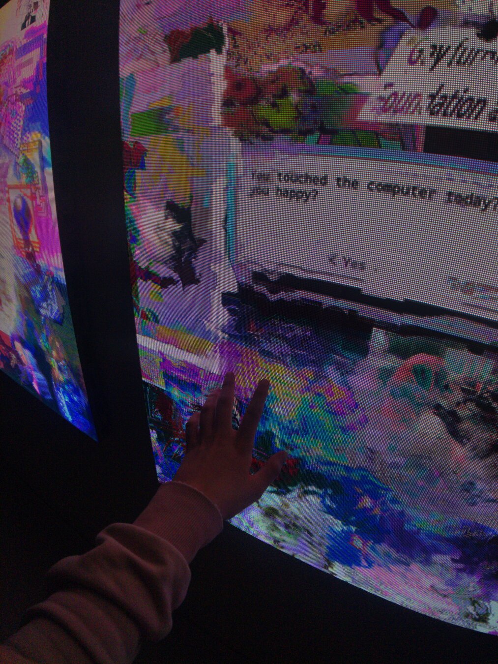 my hand reaching out to touch my artwork computer_downloads_folder.jpg, that contains an old dos style button asking "you touched the computer today, did it make you happy? yes/no"